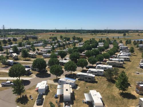 Aerial view of a large RV park with numerous parked RVs and green trees under a clear blue sky.