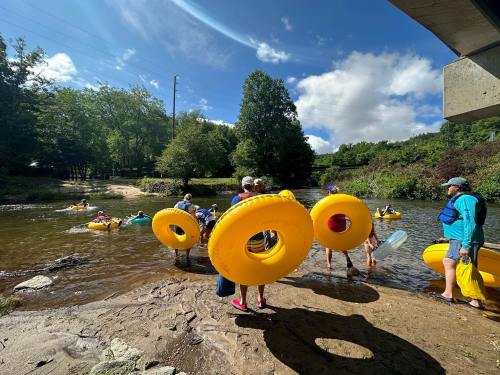 People preparing to float on yellow inner tubes in a river under a sunny sky with trees in the background.