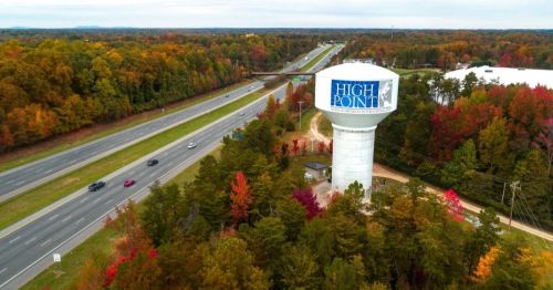 Aerial view of a water tower labeled "High Point" surrounded by colorful autumn trees and a highway.
