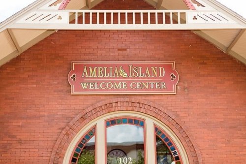 Sign for the Amelia Island Welcome Center, featuring red brick and decorative elements.