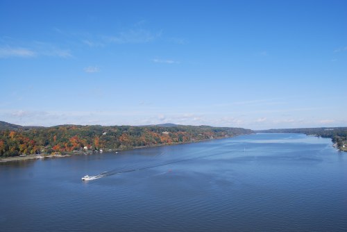 A scenic view of a river with a boat, surrounded by colorful autumn foliage and a clear blue sky.