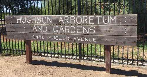 Wooden sign for Hughson Arboretum and Gardens, located at 2490 Euclid Avenue, surrounded by greenery.
