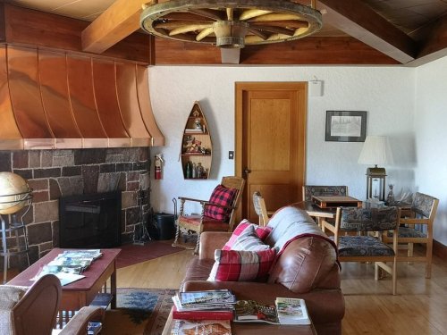 Cozy living room with a leather sofa, wooden accents, a stone fireplace, and rustic decor.