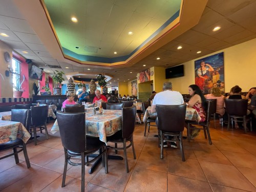 A vibrant restaurant interior with colorful decor, tables set for dining, and patrons enjoying their meals.