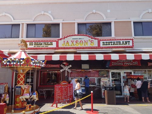 A colorful restaurant facade with a carousel, featuring "Jaxson's Ice Cream Parlor" and "Jaxson's Dining Parlor" signs.