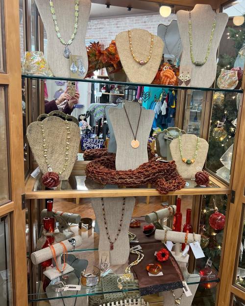 Display of various necklaces and accessories in a glass showcase, featuring different styles and colors.