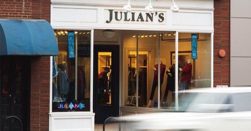 Storefront of Julian's, featuring large windows displaying clothing and a blurred car passing by.