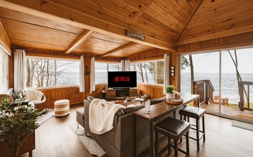 Cozy wooden living room with a view of the lake, featuring a Netflix screen and comfortable seating.