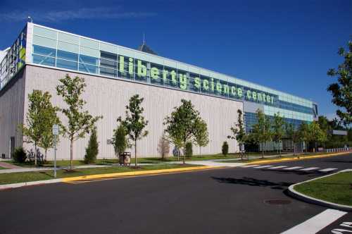 Exterior view of the Liberty Science Center, featuring modern architecture and greenery under a clear blue sky.