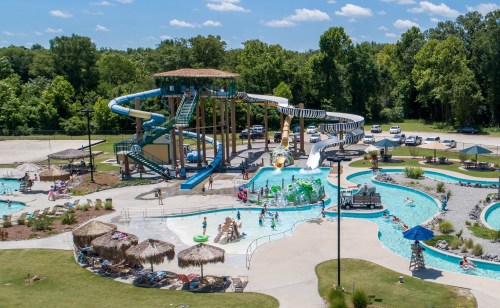 A vibrant water park featuring slides, pools, and families enjoying the sunny day amidst lush greenery.