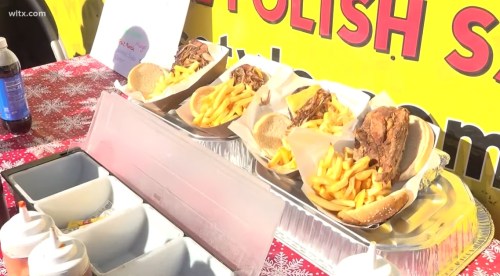 Three trays of sandwiches with fries, served at a food stand, with condiments in the foreground. Bright yellow background.