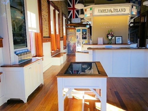 Interior of a visitor center with wooden floors, a reception desk, and informational displays about Amelia Island.