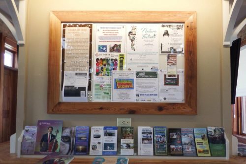 A bulletin board displaying various flyers and brochures about local events and attractions.
