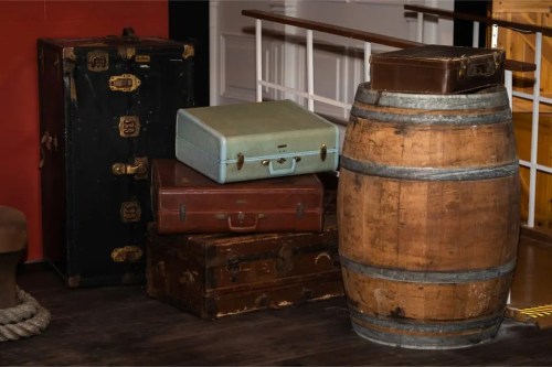 A collection of vintage suitcases and a wooden barrel arranged in a cozy indoor setting.