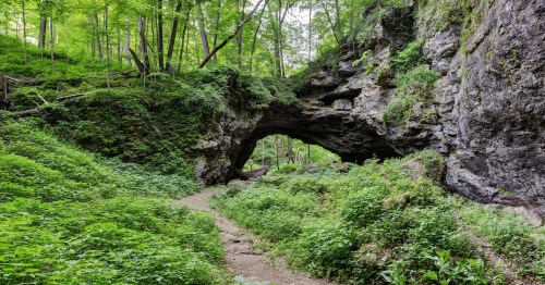 A hiking path leads under a massive natural limestone bridge at Maquoketa Caves State Park in Iowa.