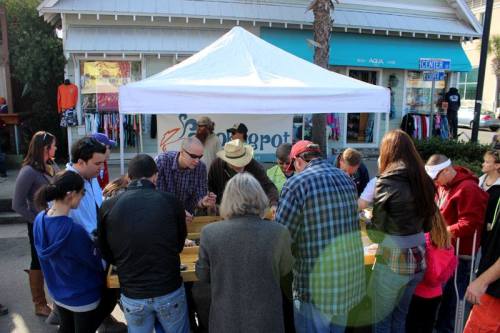 A group of people gathered around a table under a tent, engaged in an outdoor activity or event.