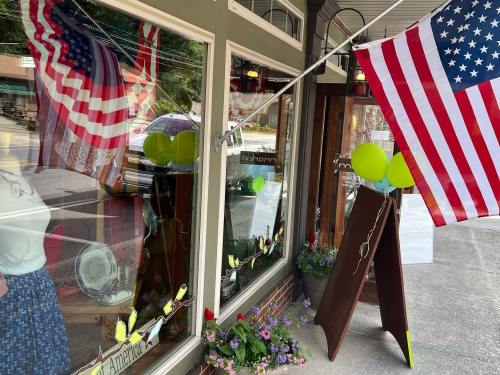 A storefront decorated with American flags, balloons, and flowers, showcasing a welcoming atmosphere.