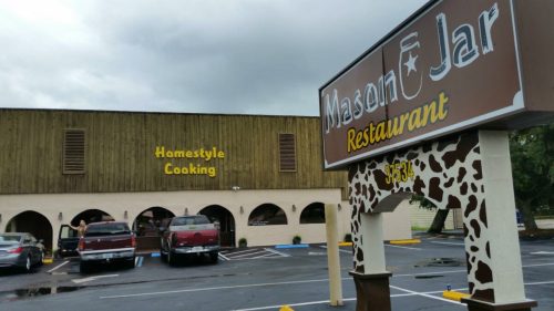 Exterior of Mason Jar Restaurant with a sign reading "Homestyle Cooking" and parked trucks in the lot.