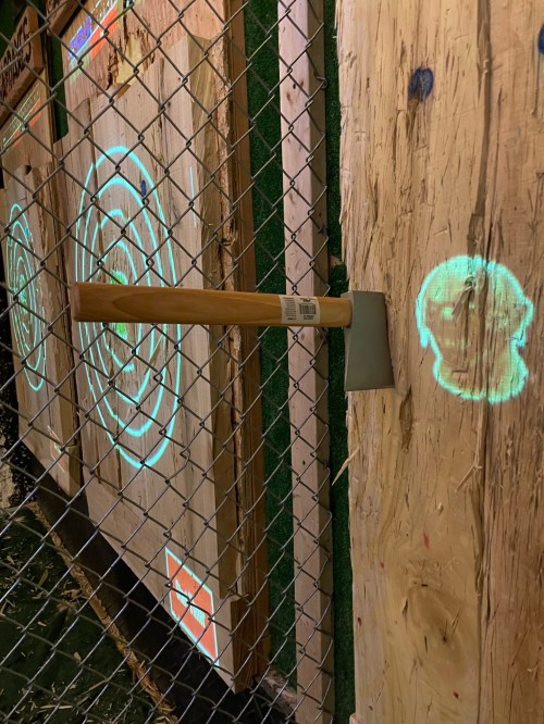 A wooden axe embedded in a target board, with glowing circular target patterns projected on the wood.