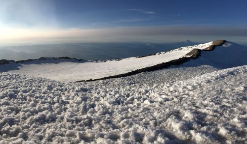 Snow-covered mountain landscape with a clear sky and distant peaks visible on the horizon.
