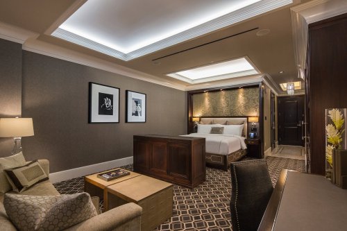 Luxurious hotel room featuring a king bed, stylish seating area, and elegant decor with modern lighting.