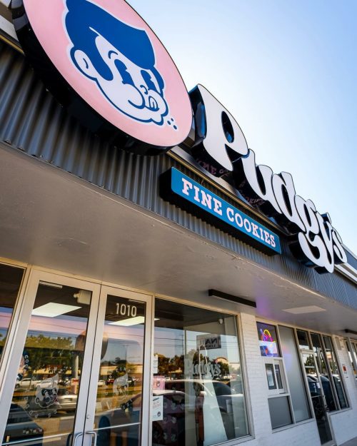 Signage of "Puggy's Fine Cookies" on a storefront, featuring a cartoonish character and a welcoming entrance.