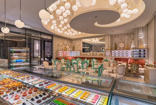 Elegant pastry shop interior featuring colorful desserts, stylish seating, and unique lighting fixtures.