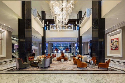 Luxurious hotel lobby featuring elegant seating, a grand chandelier, and modern decor in a spacious, stylish setting.