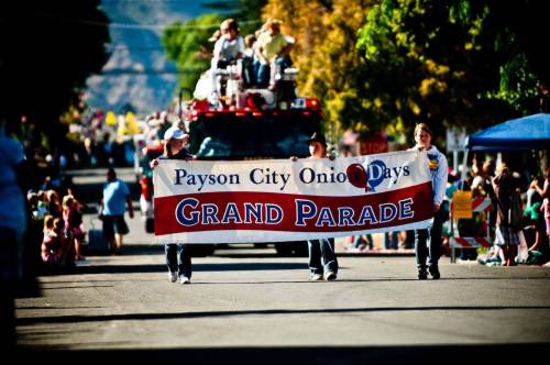 A parade scene with participants holding a banner for "Payson City Onion Days Grand Parade" amidst a festive crowd.