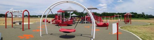 A colorful playground featuring swings, slides, and play structures under a clear blue sky.