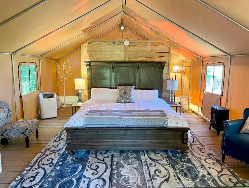 Cozy glamping tent interior featuring a large bed, lamps, and comfortable seating on a patterned rug.