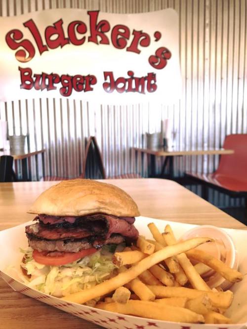 A delicious burger with lettuce, tomato, and two patties, served with a side of fries in a casual diner setting.