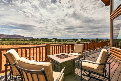 A cozy outdoor seating area with chairs and a fire pit, overlooking a scenic landscape under a cloudy sky.