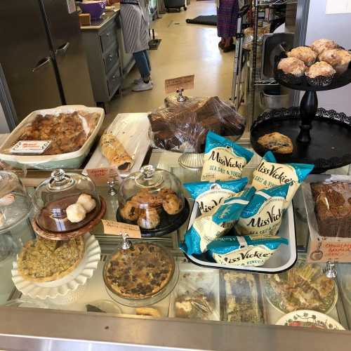 A display case filled with various baked goods, including cookies, cakes, and pastries, in a cozy bakery setting.