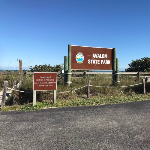Sign for Avalon State Park with blue sky and greenery in the background. Road leading to the park entrance.
