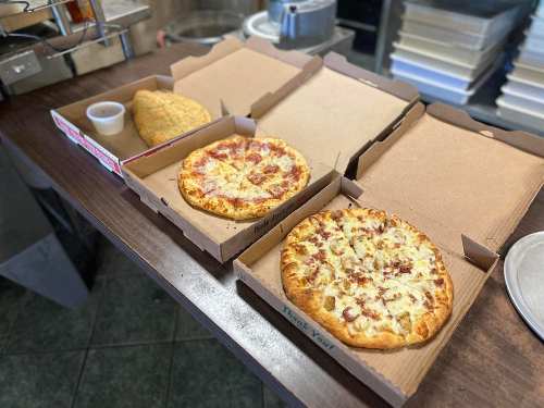 Three pizza boxes on a table: one with pepperoni, one with cheese, and a side of garlic bread.