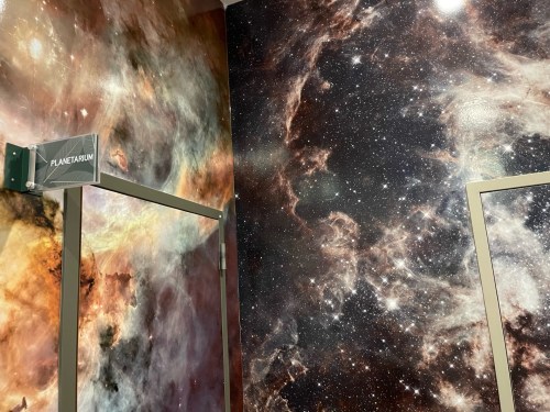 A wall featuring a vibrant cosmic mural with stars and nebulae, labeled "Planetarium" above a doorway.