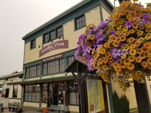 A charming general store with colorful flower baskets hanging outside, showcasing a welcoming facade.