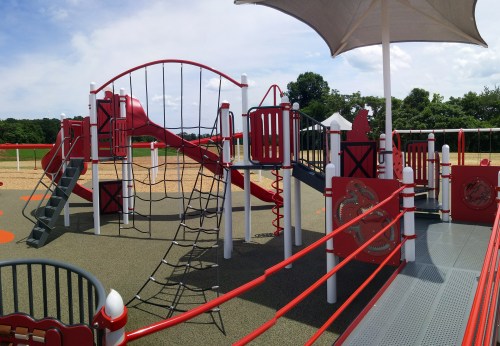 Colorful playground with slides, climbing structures, and shaded areas, set against a clear blue sky.
