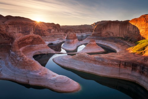A serene landscape of rock formations and a winding river at sunrise, with warm light illuminating the scene.