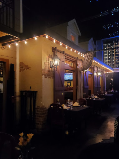 Cozy restaurant corner with warm lighting, outdoor seating, and decorative string lights at night.