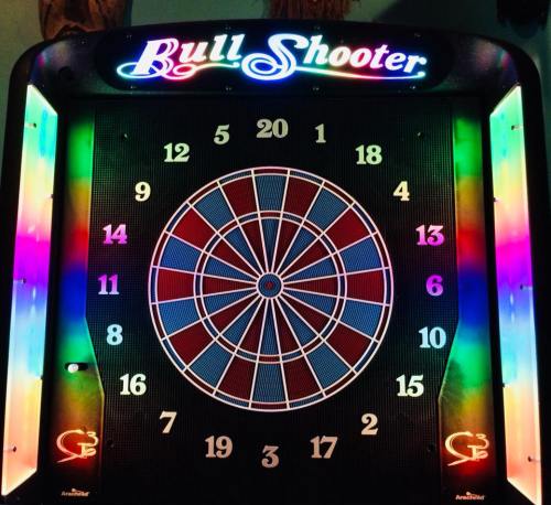 A brightly lit electronic dartboard with colorful numbers and a bullseye in the center.