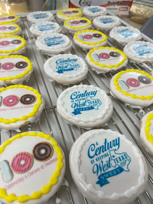 Decorated cookies on a cooling rack, featuring colorful donut designs and text celebrating West Texas.