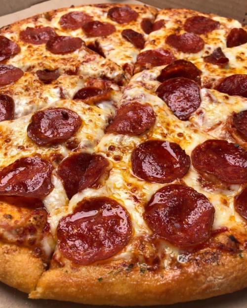 A close-up of a pepperoni pizza with melted cheese and a golden crust, sliced into eight pieces.