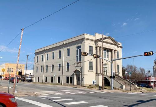 Historic building at a street corner, featuring a grand entrance and large windows, under a clear blue sky.