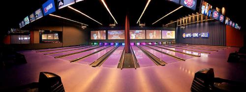 A modern bowling alley with multiple lanes, colorful lights, and large screens displaying scores and entertainment.