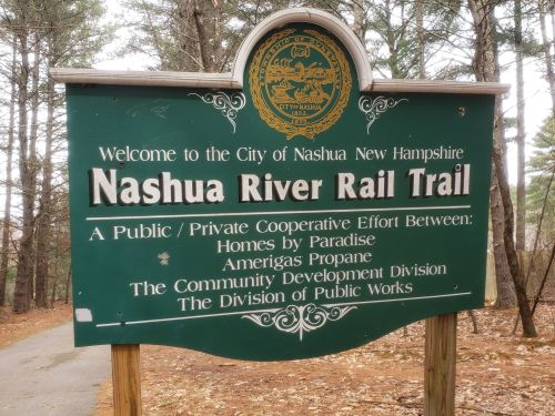 Sign welcoming visitors to the Nashua River Rail Trail in New Hampshire, detailing cooperative efforts for its development.