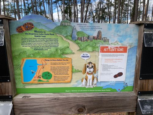 Sign at Singletary Lake State Park featuring a map, park information, and a cartoon dog with a welcome message.