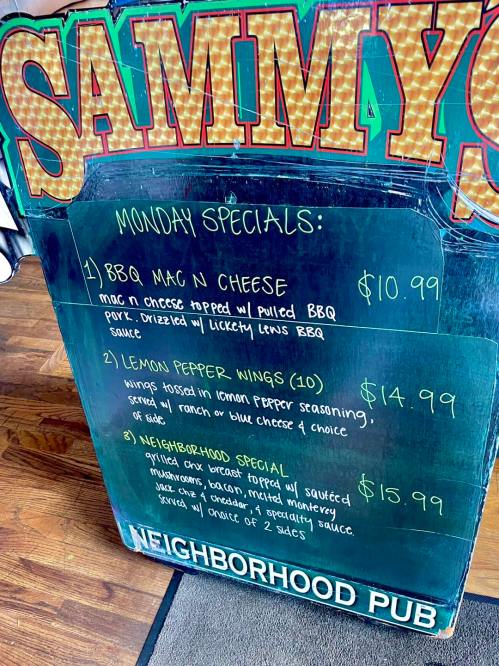 Chalkboard menu displaying Monday specials at Sammy's: BBQ Mac n Cheese, Lemon Pepper Wings, and Neighborhood Special.