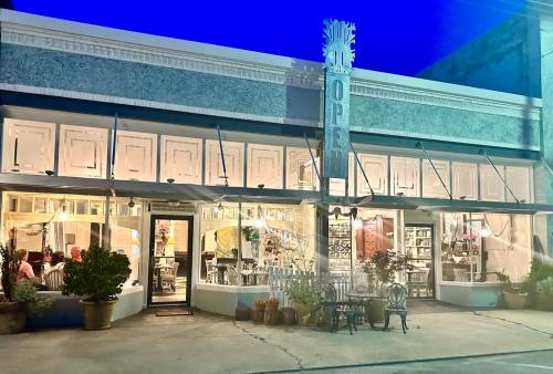 A charming restaurant with an "OPEN" sign, featuring outdoor seating and illuminated windows at dusk.